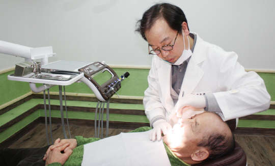 여주 룡플란트치과 이용현 원장이 노인 환자의 치아를 검진하고 있다.(룡플란트치과그룹 제공)